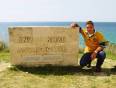A person kneeling by the ANZAC Cove sign