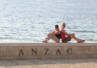 Two girls sitting on a wall at ANZAC Cove, by the sea