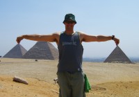 A man striking a fun pose with the Pyramids of Giza