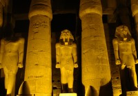 Statues of King Ramses II illuminated at night in the Luxor Temple