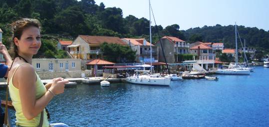 A girl viewing the boats in the port and the blue sea, from a boat