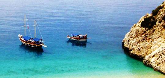 Two boats anchored where the Turquoise coast meets the sandy beach