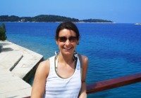 A girl on a boat smiles happily against a blue sea background