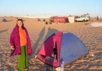 A girl standing in front of her tent in the White Desert