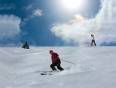 People skiing down a mountain with a sunny background
