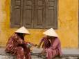 Men sitting on the street in Hoi An in conical hats