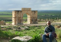 A man sits by the beautiful Ruins at Volubilis