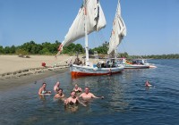 An on the go group swimming in the Nile near their felucca