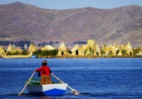 A Peruvian lady rowing out to Uros Island on Lake Titicaca, where houses are made from Totara reed
