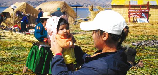 A girl holding a Peruvian baby on Taquille Island, Lake Titicaca