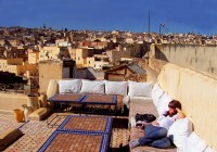 A lady relaxing in a rooftop garden, with views across Marrakech