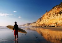 A surfer with his board, approaching the inviting sea