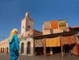 Moroccan lady and colourful rugs hanging from Marrakech's Medina walls