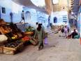 A fruit stall and Moroccan lady carrying shopping  in Chefchaouen