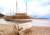 A canoe on a pebbled beach and a boat in Croatia