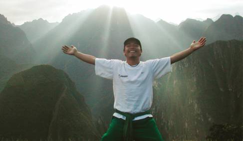 A happy man celebrating in the morning sun, at the end of Peru's Inca Trail
