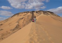 People climbing a sand dune in the Western Desert