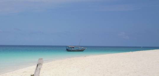 White sands and crystal clear waters of the beaches of Zanzibar with a traditional dhow