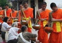 Orange clad monks in Laos collecting alms from worshippers. A common sight in Laos.