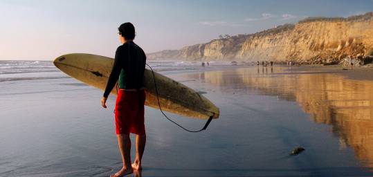 Man carrying his surf board into the sea in Morocco