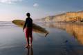 Man carrying his surf board into the sea in Morocco