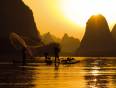 Fisherman on a boat at sunrise in Guilin with its karst limestone outcrops