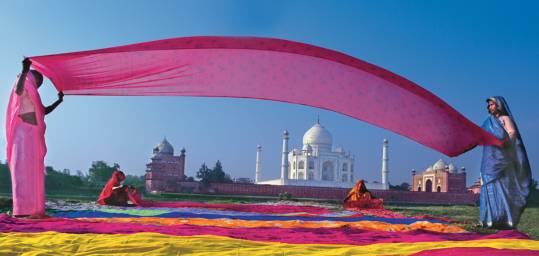 Indian women with brightly coloured materials, in front of the Taj Mahal