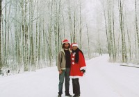 A couple standing in a snowy forest, the girl is wearing a santa suit!
