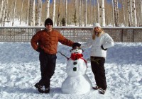 A couple stand by their wonderful snowman
