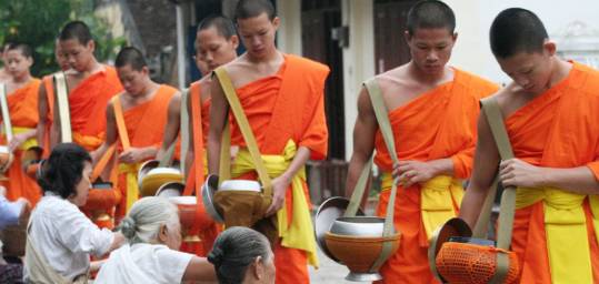 Orange clad monks in Laos collecting alms from worshippers. A common sight in Laos. 