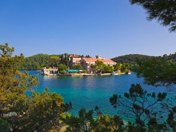 Aerial view of Dubrovnik, surrounded by water and filled with terracotta-roofed buildings