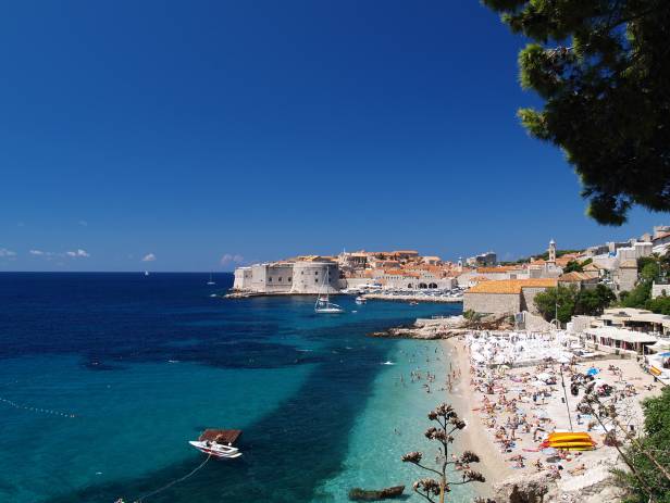 Aerial view of Dubrovnik, surrounded by water and filled with terracotta-roofed buildings