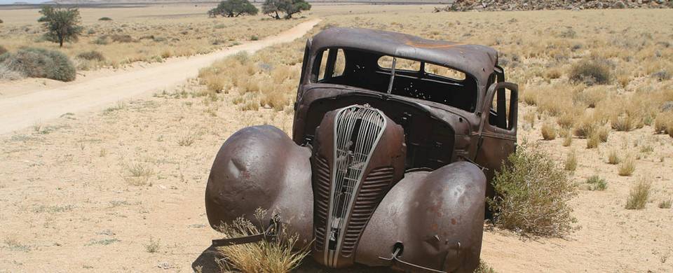 Rusted old fashioned car abandoned at the side of the road