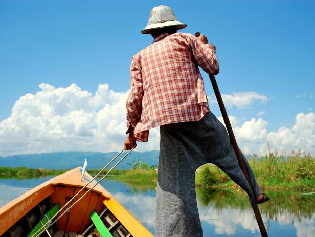 Fisherman pushing his boat in the unique style used on Inle Lake