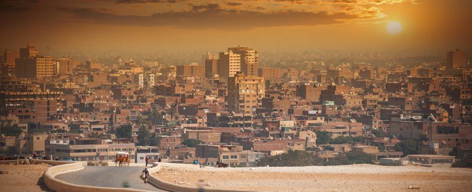 The city of Cairo at the end of a dusty path in front of the setting sun