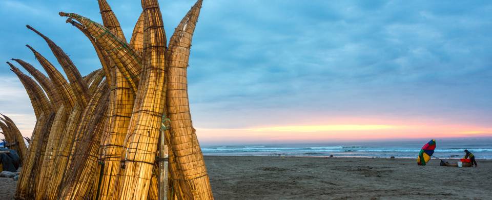 Straw boats in the sand at the beach in Chiclayo at sunset