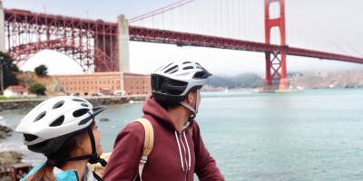 Young couple on a bike tour of San Francisco admiring the Golden Gate Bridge