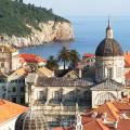 Aerial view of Dubrovnik, surrounded by water and filled with terracotta-roofed buildings