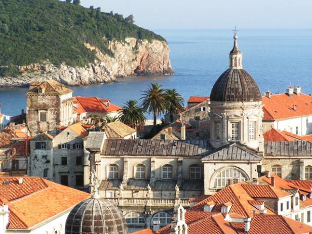 Aerial view of Dubrovnik, surrounded by water and filled with terracotta-roofed buildings