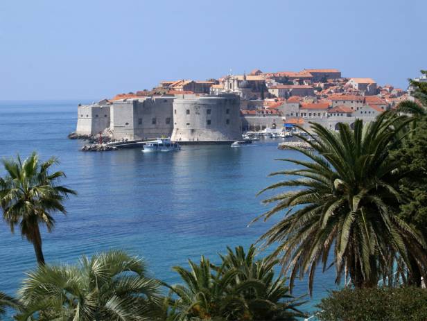 Aerial view of Dubrovnik, surrounded by water and filled with terracotta-roofed buildings