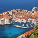 Aerial view of Dubrovnik, surrounded by water and filled with terracotta-roofed buildings