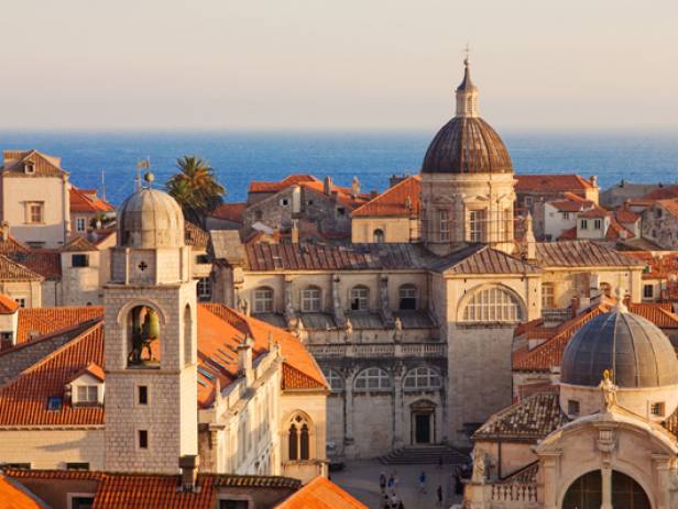 Aerial view of Dubrovnik, surrounded by water and filled with terracotta-roofed buildings