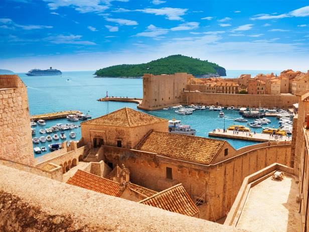 Aerial view of Dubrovnik, surrounded by water and filled with terracotta-roofed buildings