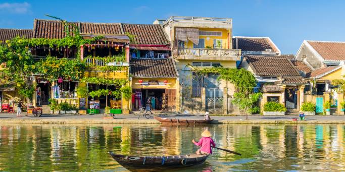 A traditional longboat sails along the river in Hoi An