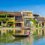 A traditional longboat sails along the river in Hoi An