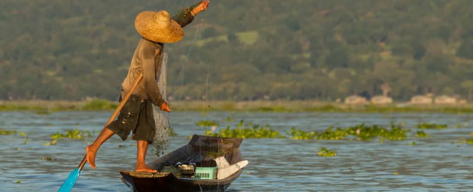 Fisherman pushing his boat in the unique style used on Inle Lake