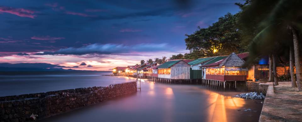 Night time in Kep as light from the village reflect off the water and a purple streak across the sky