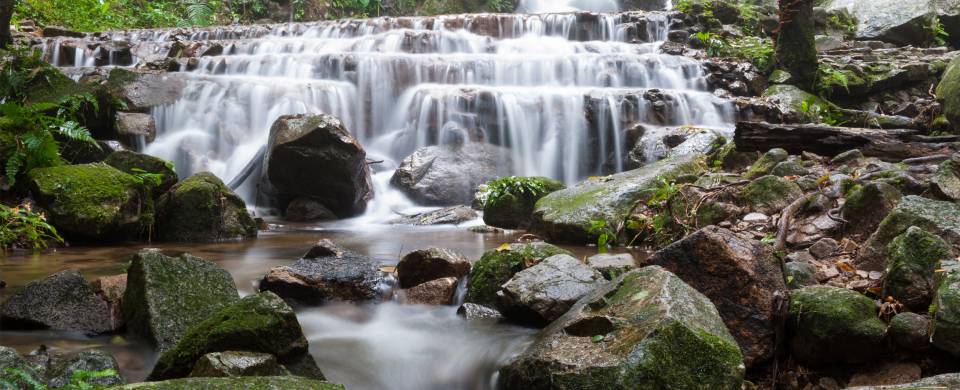 Water cascades over glistening rocks in the jungle that surrounds the village of Mae Kampong in nort