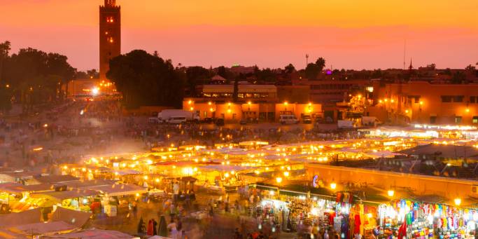 The sun begins to set over the twinkling lights of djemaa el fna square in Marrakech