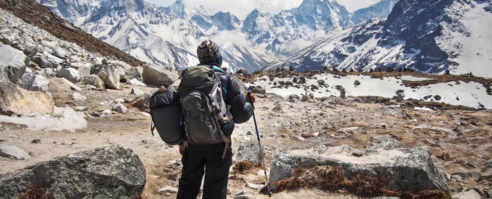 Hiker at Mount Everest Base Camp, looking at the snow-capped peaks of the Himalayas